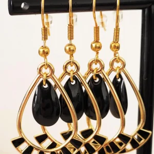 Boucles d'oreilles noires et dorées, légères à porter, en forme de gouttes, avec une pampille noire au milieu et des crochets pour attaches.