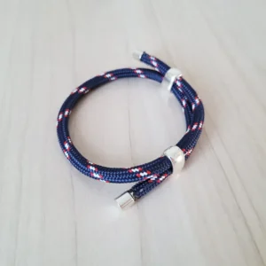 Bracelet coulissant en paracorde (ou corde) bleu marine, avec des dessins blancs et rouges réguliers, 2 poussoirs pour régler le bracelet et 2 embouts en métal à chaque bout.