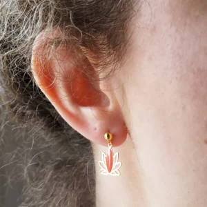 Clous d'oreilles dorées avec un pendant en forme de lotus ajouré de couleur doré et corail.