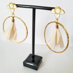 Boucles d'oreilles pendantes avec des supports en formes de 3 coeurs colorés en blanc et dorés. Ces supports ont un anneau martelé et un pompon en imitation satin de couleur beige à l'intérieur.