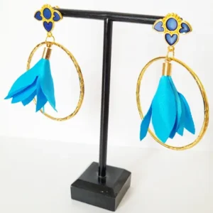 Boucles d'oreilles pendantes avec des supports en formes de 3 coeurs colorés en bleu et dorés. Ces supports ont un anneau martelé et un pompon en imitation satin de couleur bleu à l'intérieur.