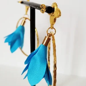 Boucles d'oreilles pendantes avec des supports en formes de 3 coeurs colorés en bleu et dorés. Ces supports ont un anneau martelé et un pompon en imitation satin de couleur bleu à l'intérieur.