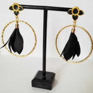 Boucles d'oreilles pendantes avec des supports en formes de 3 coeurs colorés en noir nacré et dorés. Ces supports ont un anneau martelé et un pompon en imitation satin de couleur noir à l'intérieur.