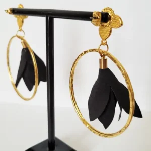 Boucles d'oreilles pendantes avec des supports en formes de 3 coeurs colorés en noir nacré et dorés. Ces supports ont un anneau martelé et un pompon en imitation satin de couleur noir à l'intérieur.