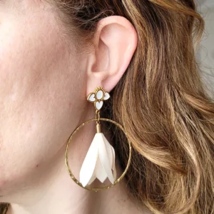 Boucles d'oreilles pendantes avec des supports en formes de 3 coeurs colorés en blanc et dorés. Ces supports ont un anneau martelé et un pompon en imitation satin de couleur beige à l'intérieur.