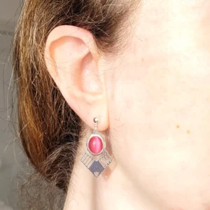 Vue portée des boucles d'oreilles argentées pendantes avec cabochon ovale roser en verre et triangle argenté ajouré