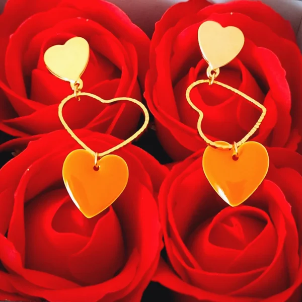 Boucles d'oreilles dorées, pendantes avec un coeur ciselé doré et un sequin en forme de coeur orange