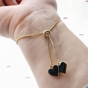 Bracelet réglable avec un coeur doré noir en pixel et des pampilles en forme de coeurs noirs et dorés